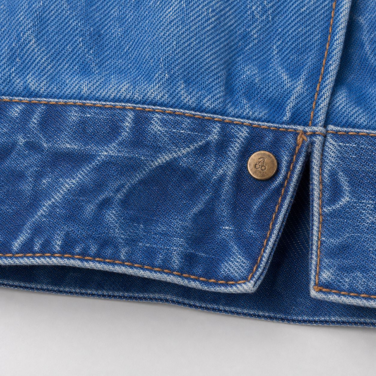 Custom cherry-marked rivet at the cuff opening, macro.