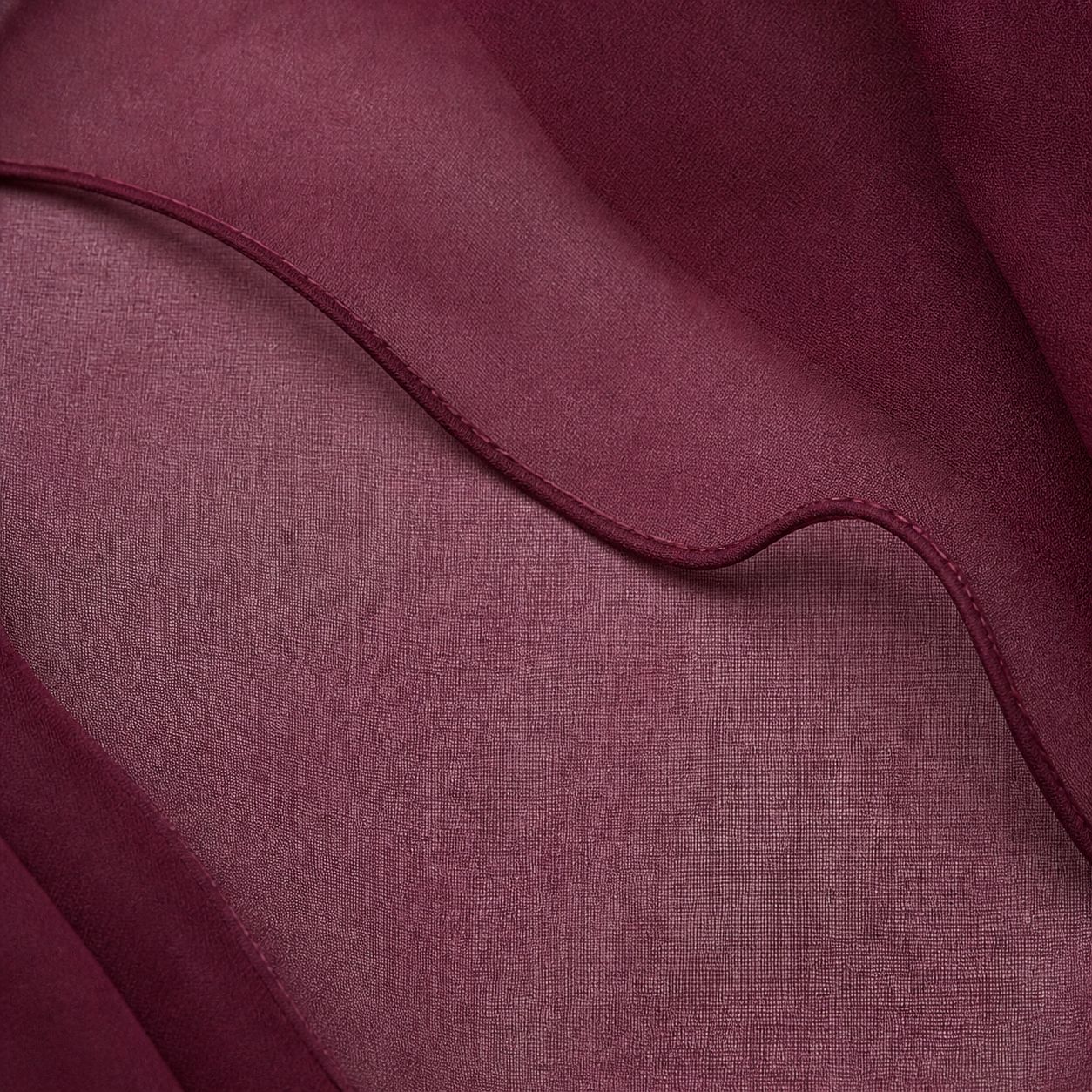Macro of the Dahlia gown hem - piped rolled edge curving through layered semi-sheer chiffon
