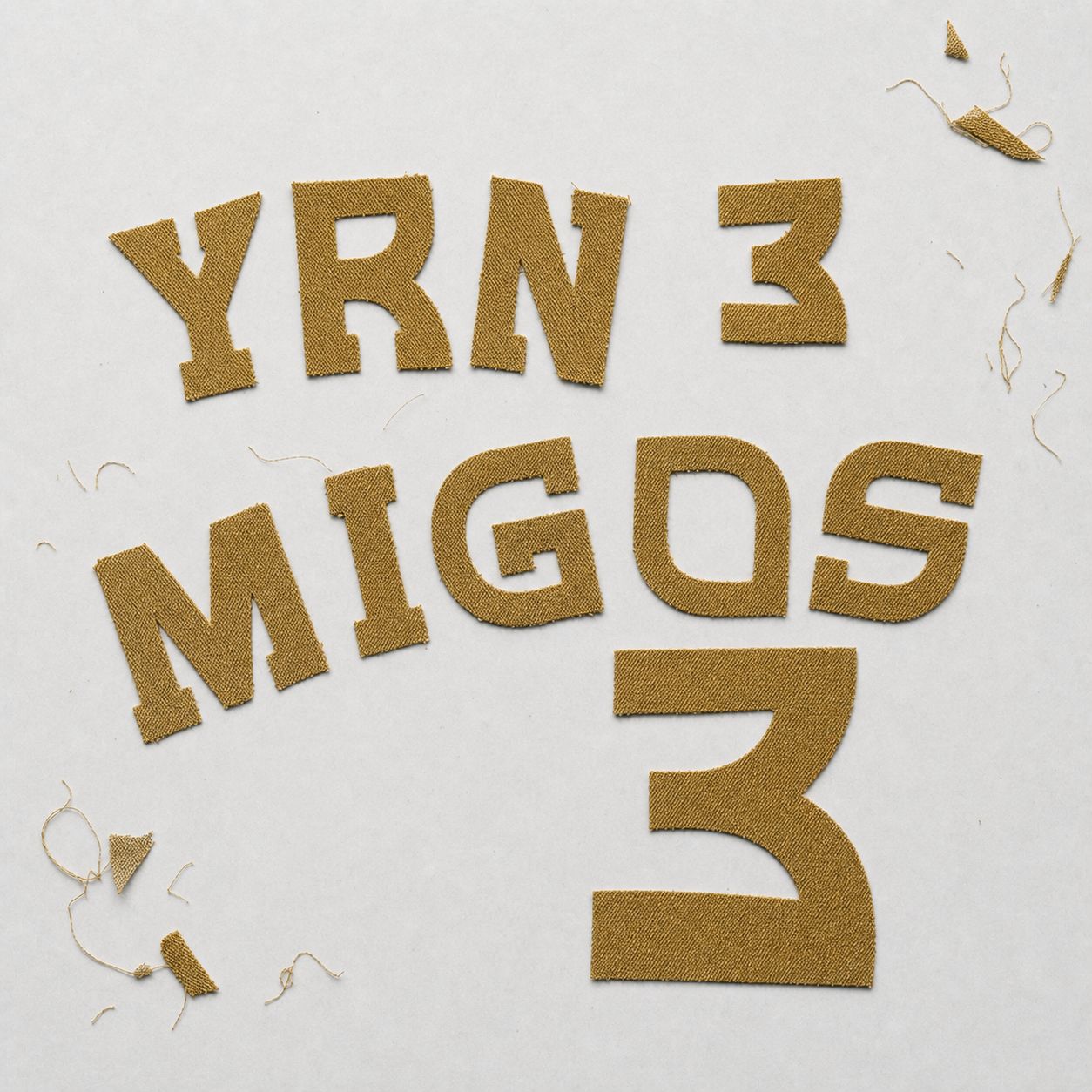 Metallic gold tackle twill YRN, MIGOS and number 3 letters, cut and unsewn with frayed edges and loose threads.