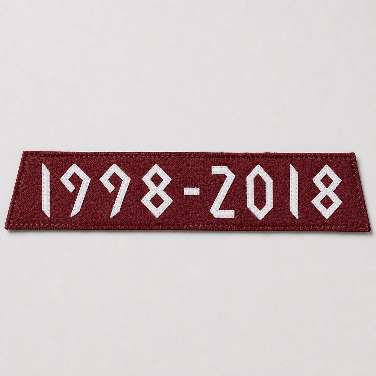 Maroon tackle twill shoulder band with white 1998–2018 lettering, pre-application.